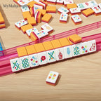 MyMahjongSet acrylic mahjong tiles with colorful floral and bamboo patterns on a pink rack
