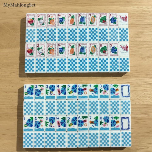 Blue gingham American mahjong tiles with colorful travel and beach vacation icons on a wooden surface