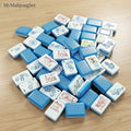 Blue vertical stripe acrylic American mahjong tiles with floral and geometric patterns on a wooden table