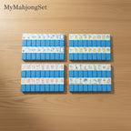 Blue vertical stripe American mahjong tiles with floral and decorative patterns arranged on a wooden table