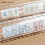 MyMahjongSet white pearl acrylic mahjong tiles with blue and red engravings displayed on clear racks