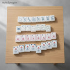 MyMahjongSet American mahjong tiles with white pearl finish and colorful engraved symbols on a wooden table